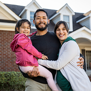 Happy family standing in front of a house